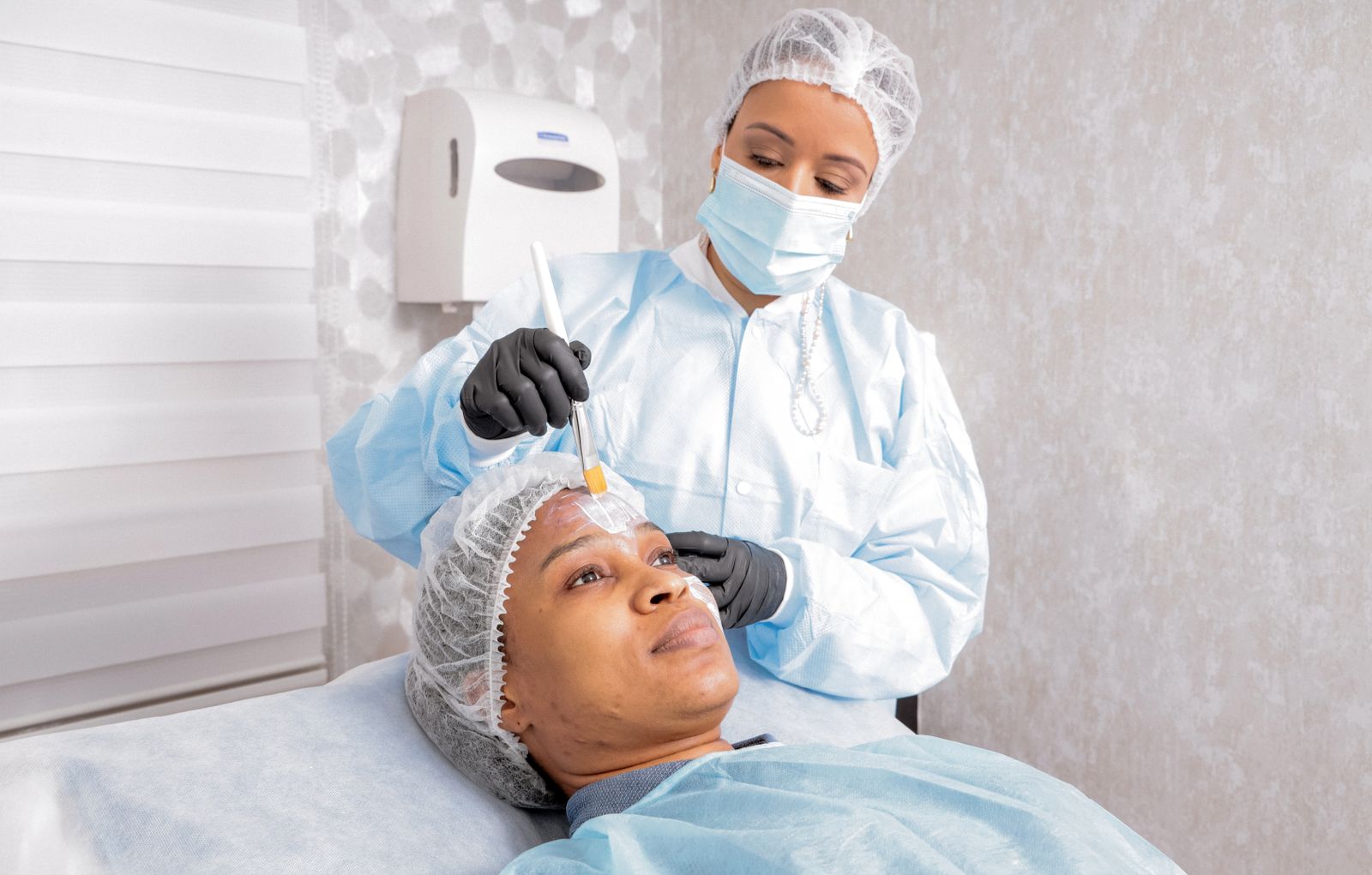 Una profesional aplica una mascarilla facial a una clienta en un centro de estética.
